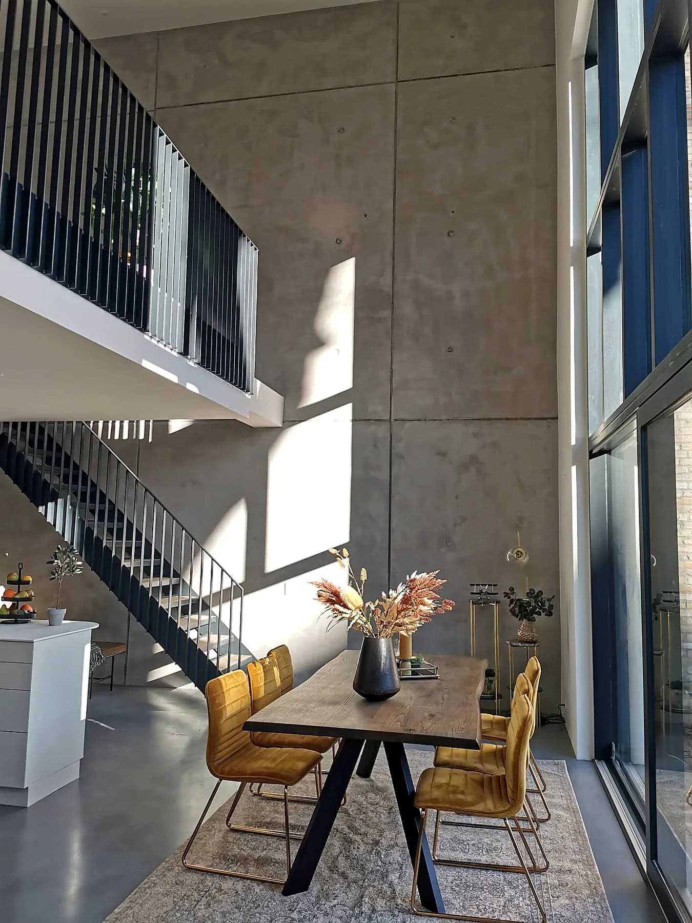 Spiseplads ved store vinduer og indvendig trappe i Atelierhaven