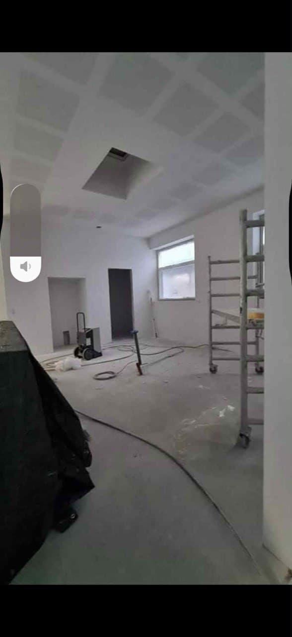 Stort rum med sprøjtespartlet loft og stige — professionel loftfinish