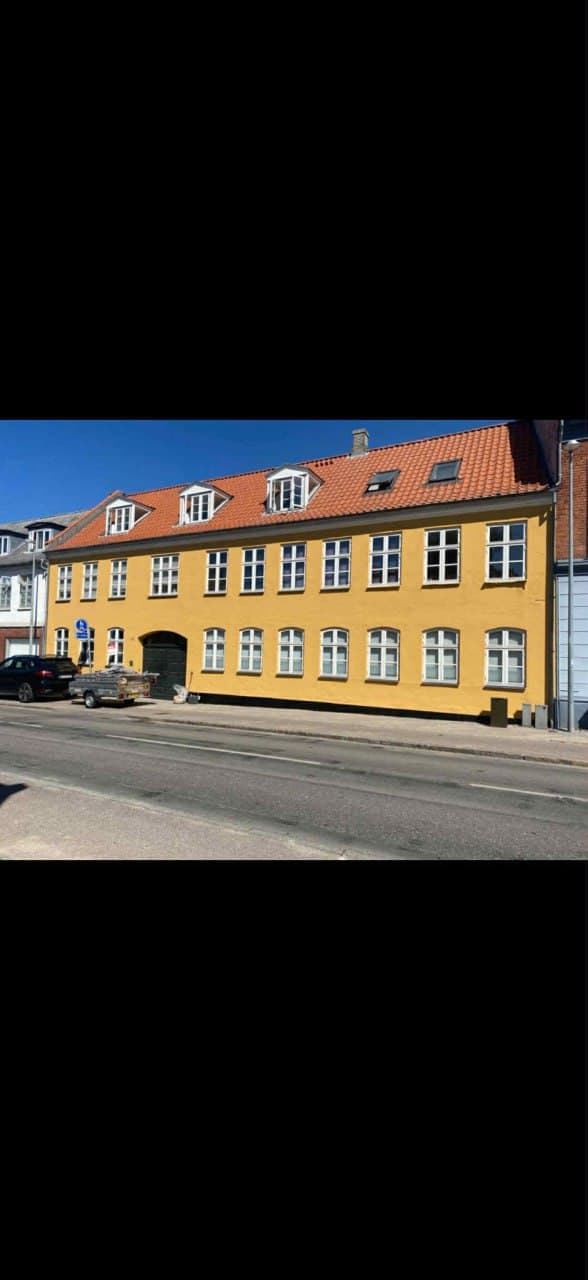 Gul pudset facade med rødt tegltag og hvide vinduer — udvendig facademaling